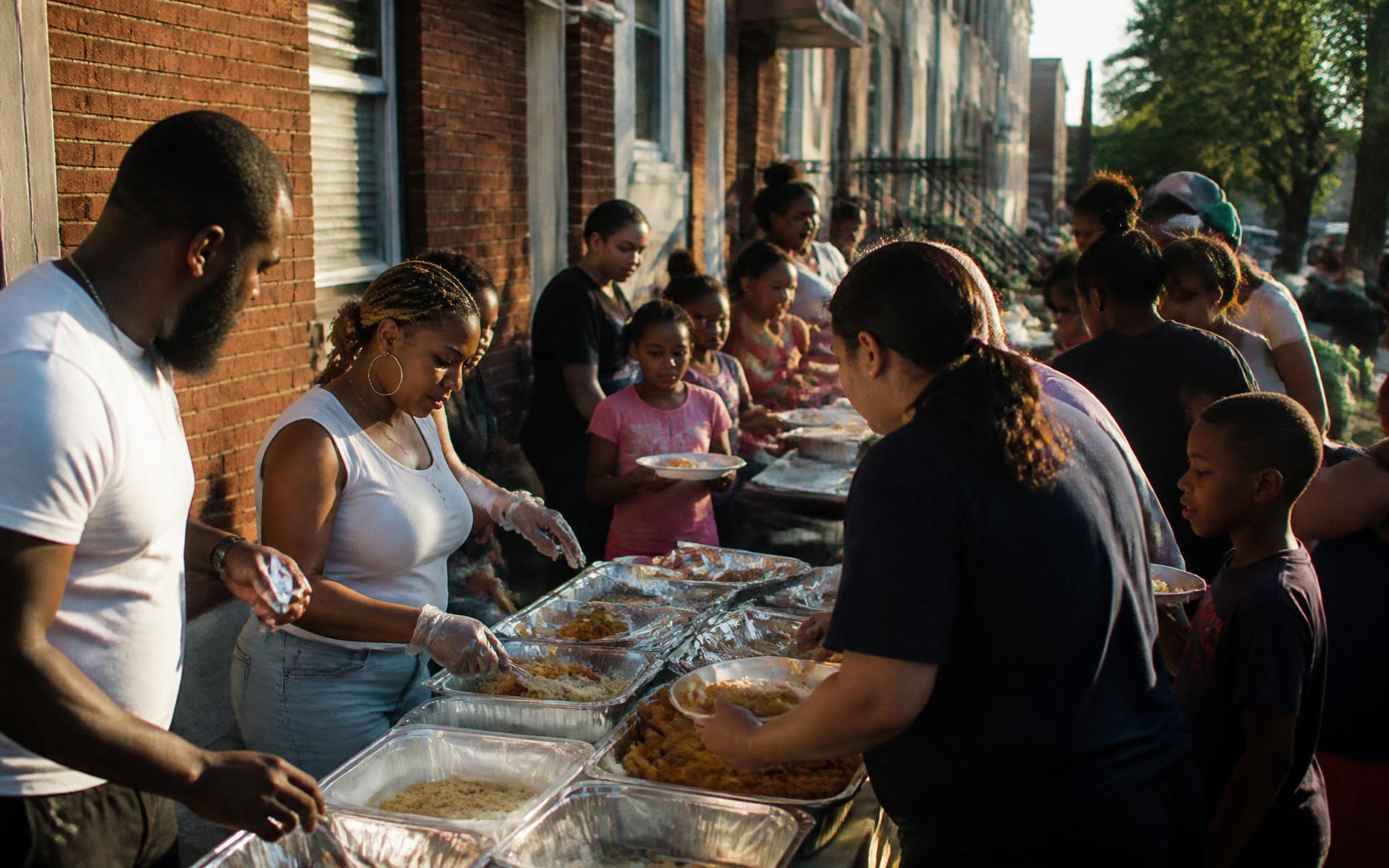Neighbors and volunteers sharing a meal together on a Baltimore sidewalk
